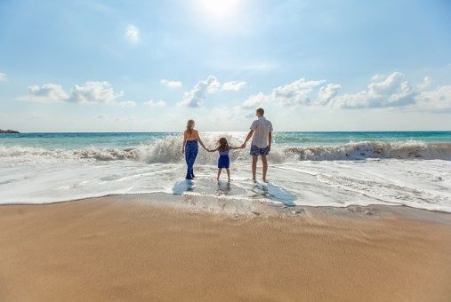 a family on holiday holding hands at a sunny beachfront 